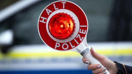 Eine Polizistin hält während einer Verkehrskontrolle eine Polizeikelle mit der Aufschrift „Halt Polizei“ (Symbolbild).