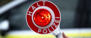 Eine Polizistin hält während einer Verkehrskontrolle eine Polizeikelle mit der Aufschrift „Halt Polizei“ (Symbolbild).