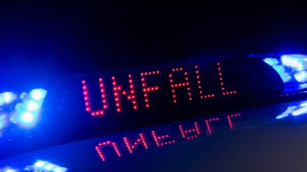 Das Blaulicht auf einem Fahrzeug der Polizei leuchtet in der Dunkelheit, während auf dem Display der Hinweis «Unfall» zu lesen ist. (Symbolbild)