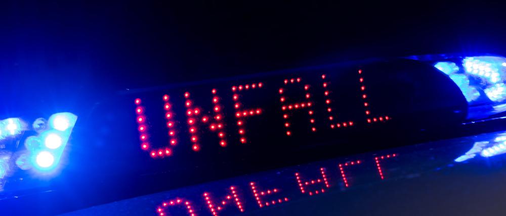 Das Blaulicht auf einem Fahrzeug der Polizei leuchtet in der Dunkelheit, während auf dem Display der Hinweis «Unfall» zu lesen ist. (Symbolbild)