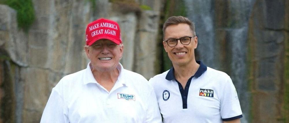 Donald Trump zeigt den Daumen hoch, neben ihm steht der finnische Präsident Alexander Stubb in Mar-a-Lago, Palm Beach. Beide halten Golfschläger in der Hand.