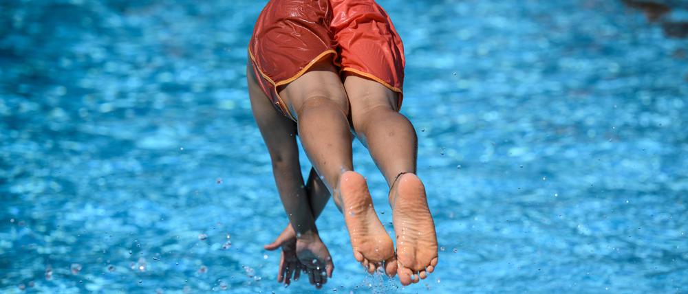 Ein Junge springt im Sommerbad Neukölln ins Schwimmbecken.