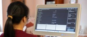 Pflegefachkraft Janna Santos ruft in einer gestellten Szene im Altenwohn- und Pflegeheim das Muster eines Krankenblatts am Teledoc-Rollständer auf.