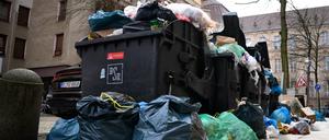 Überquellende Mülltonnen stehen auf einem Gehweg in Berlin-Moabit.  