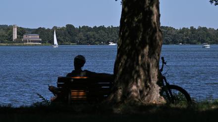 Eine Person sitzt auf einer Bank am Potsdamer Jungfernsee.