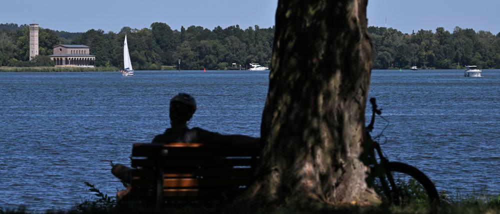 Eine Person sitzt auf einer Bank am Potsdamer Jungfernsee.