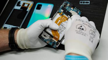In einer Werkstatt wird ein altes Smartphone wiederaufbereitet. 