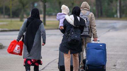 Migranten verlassen mit Reisegepäck das Gelände der Zentralen Ausländerbehörde Brandenburgs (ZABH).