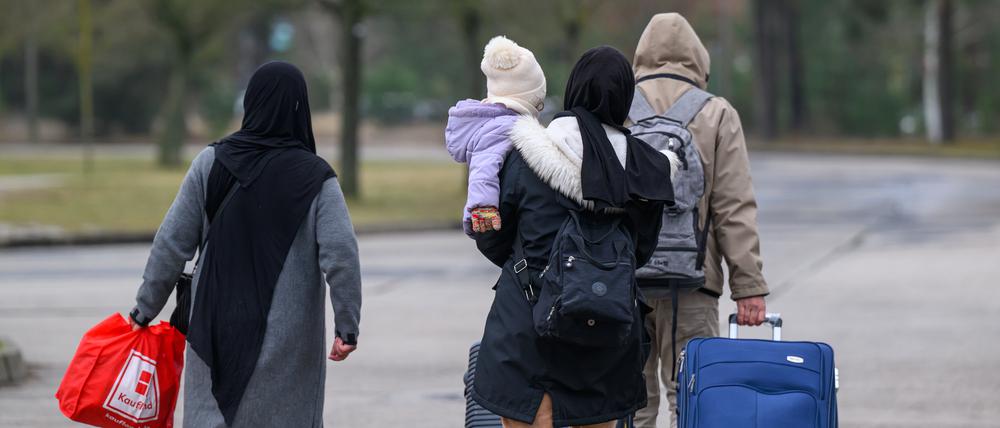 13.03.2025, Brandenburg, Eisenhüttenstadt: Migranten verlassen mit Reisegepäck das Gelände der Zentralen Ausländerbehörde Brandenburgs (ZABH). Brandenburg geht einen neuen Weg für schnellere Rückführungen von Asylbewerbern nach Polen. Ein neues sogenanntes «Dublin-Zentrum» für eine schnellere Rückführung von Asylsuchenden in andere EU-Staaten nimmt die Arbeit auf. Dort sollen Überstellungen nach Polen beschleunigt organisiert werden. Es geht um sogenannte Dublin-Fälle, also um Menschen, die ihr Asylverfahren in einem anderen EU-Staat durchlaufen müssen. Foto: Patrick Pleul/dpa +++ dpa-Bildfunk +++