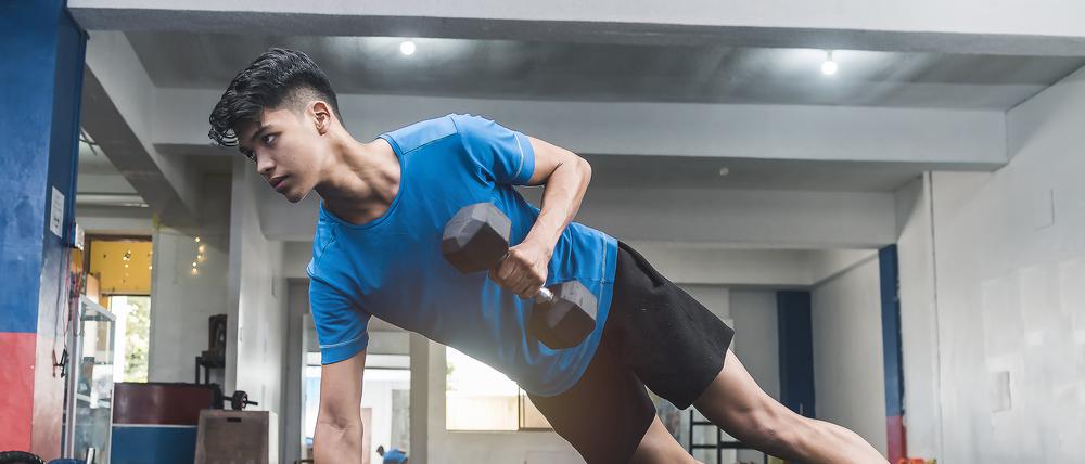 Ein Jugendlicher trainiert in einem Studio mit Hanteln.
