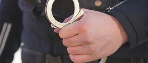 Ein Polizist hält Handschellen in der Hand.