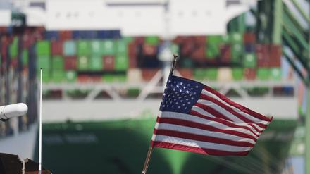 Eine US-Flagge weht vor einem Containerschiff im Hafen von Los Angeles.