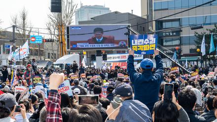 Südkoreanische Schaulustige beobachten in Seoul den Gerichtsprozess gegen den abgesetzten Präsidenten Yoon Suk Yeol.
