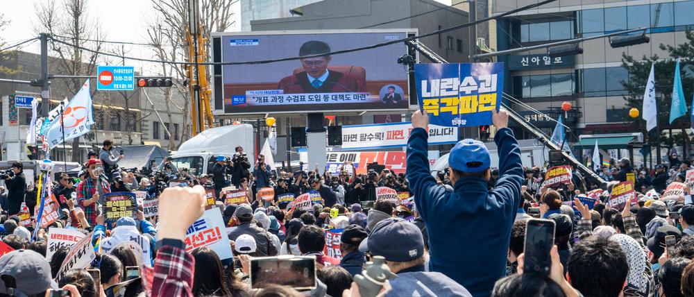 Südkoreanische Schaulustige beobachten in Seoul den Gerichtsprozess gegen den abgesetzten Präsidenten Yoon Suk Yeol.