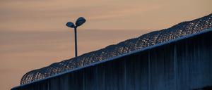 Sachsen-Anhalt, Burg: Der Tag bricht über der drahtbewährten Mauer der Justizvollzugsanstalt Burg an.