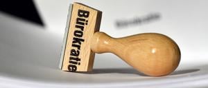 Ein Stempel mit der Aufschrift «Bürokratie» liegt auf Papieren. 
