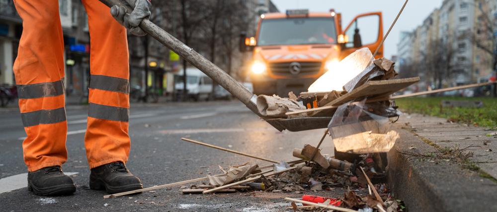 Ein Mitarbeiter der Berliner Stadtreinigung BSR räumt abgebranntes Feuerwerk von einer Straße.