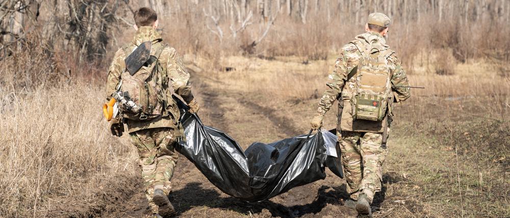 Freiwillige der Organisation Platsdarm tragen die Überreste eines russischen Soldaten. 