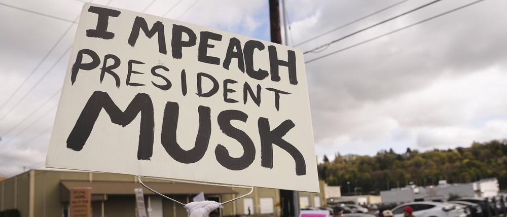 Archivbild: Eine Person schwenkt ein „Impeach President Musk“-Schild während eines Protests gegen Tesla und Elon Musk. 