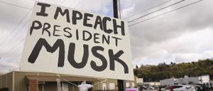 Archivbild: Eine Person schwenkt ein „Impeach President Musk“-Schild während eines Protests gegen Tesla und Elon Musk. 