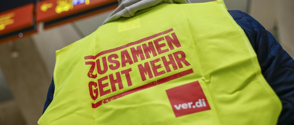 Ein Mann, der eine Warnweste mit der Aufschrift ·Zusammen geht mehr· trägt, steht im Terminal des Flughafens Köln Bonn. 