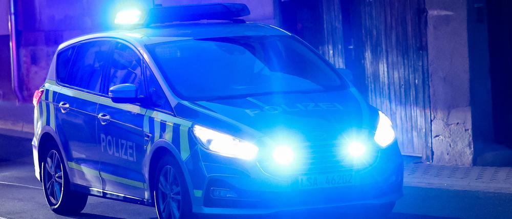 Ein Fahrzeug der Polizei fährt mit Blaulicht am Abend durch eine Straße.