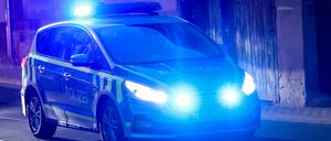Ein Fahrzeug der Polizei fährt mit Blaulicht am Abend durch eine Straße. 