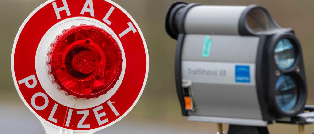 Ein Polizist hält eine Kelle zum Anhalten von Autos und ein Geschwindigkeitsmessgerät.