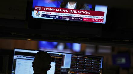 ARCHIV - 03.04.2025, USA, New York: Auf einem Bildschirm werden Finanznachrichten angezeigt, während Händler auf dem Parkett der New Yorker Börse arbeiten. Mit Aktienverkäufen in großem Stil haben Investoren auf ebenso umfangreiche wie hohe Importzölle der Regierung Trump reagiert. (zu dpa: «Weißes Haus dementiert Gerüchte über 90-Tage-Pause für Zölle») Foto: Seth Wenig/AP/dpa +++ dpa-Bildfunk +++