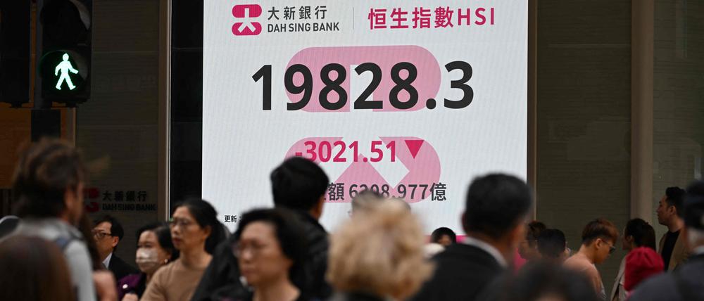 Passanten in Hongkong vor einer Leuchtanzeige mit dem Hang-Seng-Index.