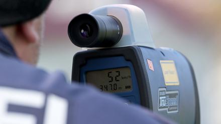 Brandenburg, Fehrbellin: Ein Polizist misst mit einem Lasermessgerät die Geschwindigkeit von Verkehrsteilnehmern im Ortsteil Linum.