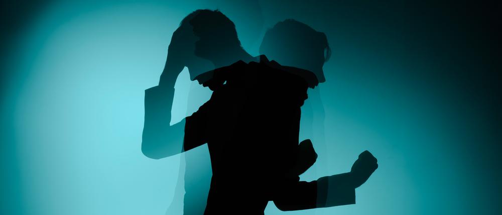 Zweigeteilter Schatten eines Mannes. Einer hält sich die Hand an den Kopf, der andere reckt wütend die Faust.