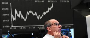 Ein Börsenhändler beobachtet auf dem Parkett der Frankfurter Wertpapierbörse vor der Anzeigetafel mit der Dax-Kurve seine Monitore.
