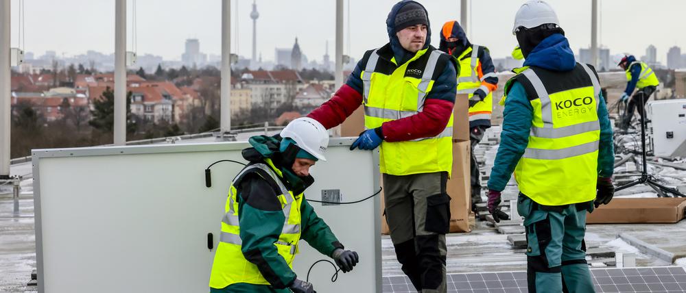 Monteure installieren eine Solaranlage auf dem Olympiastadion.