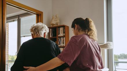 Eine junge Pflegerin hilft einer alten Frau zuhause.
