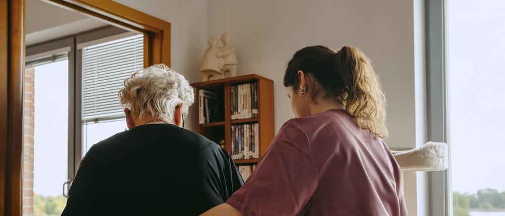Eine junge Pflegerin hilft einer alten Frau zuhause.