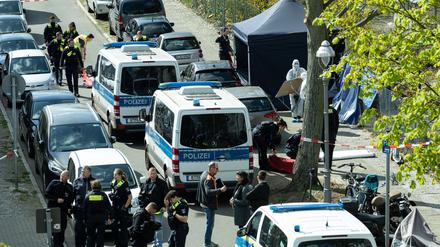 Polizisten und Beamte der Spurensicherung in weißen Schutzanzügen stehen an dem Ort, wo ein toter Mann gefunden wurde. 