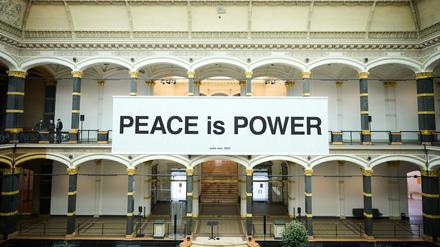 Im Lichthof des Gropius Baus hängt die Friedensbotschaft „Peace is Power“.