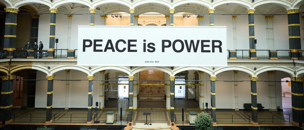 Im Lichthof des Gropius Baus hängt die Friedensbotschaft „Peace is Power“.