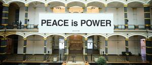 Im Lichthof des Gropius Baus hängt die Friedensbotschaft „Peace is Power“.