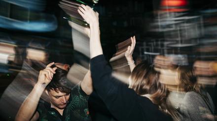 Junge Menschen feiern ausgelassen auf einer Club-Tanzfläche.