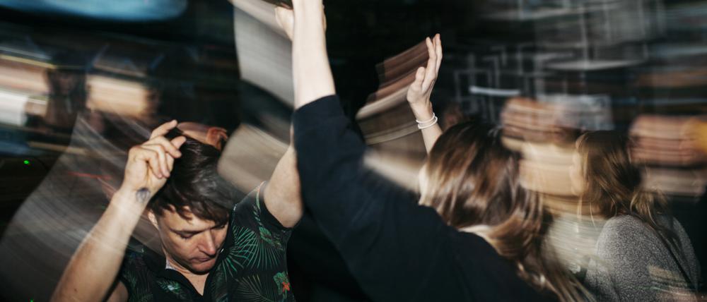 Junge Menschen feiern ausgelassen auf einer Club-Tanzfläche.