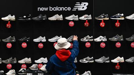Eine Frau kauft New Balance-Sneakers, die in einem Einkaufszentrum in Peking zum Verkauf angeboten werden.