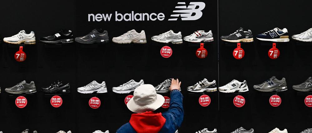 Eine Frau kauft New Balance-Sneakers, die in einem Einkaufszentrum in Peking zum Verkauf angeboten werden.