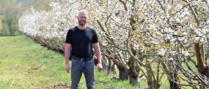 Stephan Ohlemann, Hofbetreiber von Neumanns Erntegarten, steht in den Reihen seiner blühenden Obstbäume.