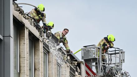  Feuerwehrleute löschen auf einem Geschäftsgebäude in Berlin-Tiergarten die Reste eines Brands. 