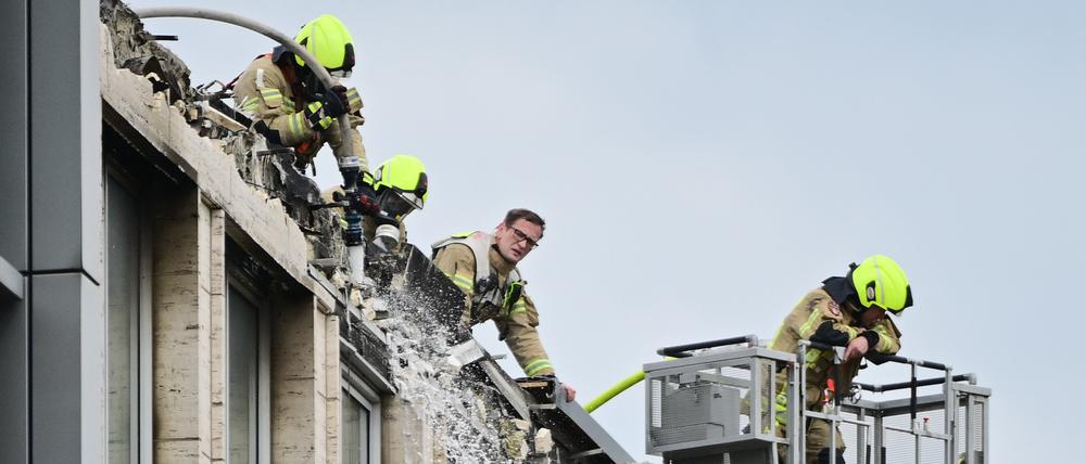  Feuerwehrleute löschen auf einem Geschäftsgebäude in Berlin-Tiergarten die Reste eines Brands. 