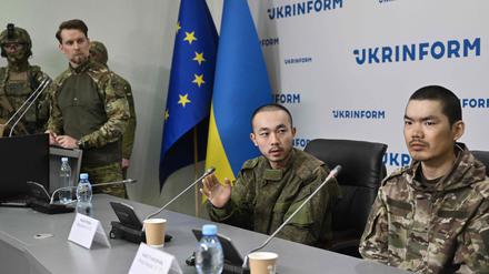 Die chinesischen Staatsangehörigen Zhang Renbo (C) und Wang Guangjun (R) schauen während einer Pressekonferenz in Kiew am 14. April 2025 inmitten der russischen Invasion in der Ukraine zu.  
