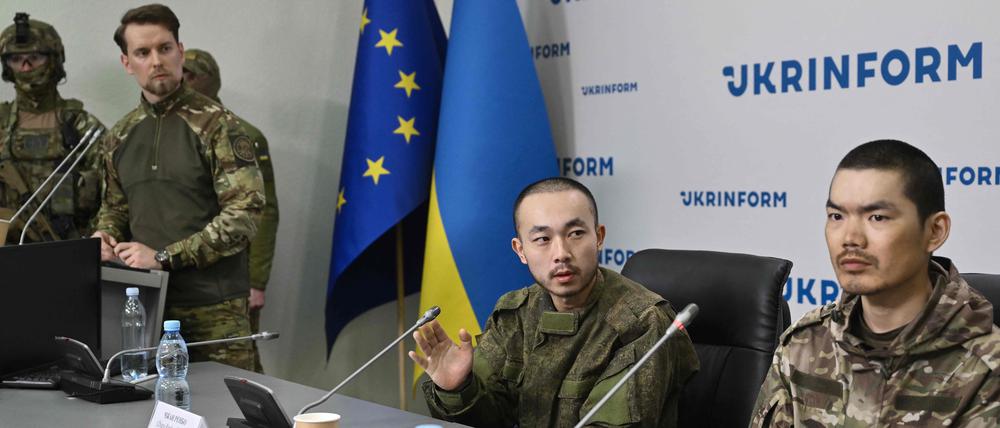 Die chinesischen Staatsangehörigen Zhang Renbo (C) und Wang Guangjun (R) schauen während einer Pressekonferenz in Kiew am 14. April 2025 inmitten der russischen Invasion in der Ukraine zu.  