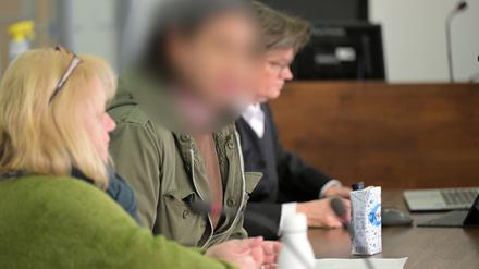 Die angeklagte Frau sitzt neben einer Dolmetscherin und ihrer Verteidigung in einem Verhandlungssaal in einem Landgericht. 